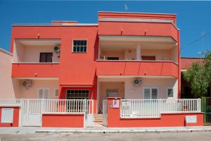 una casa rossa con balconi bianchi su una strada di b&b Rita, nel cuore del Salento a Cavallino di Lecce