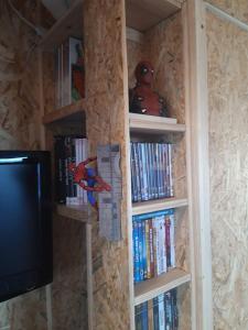 a book shelf filled with books next to a tv at Home for Geeks in Le Bélieu