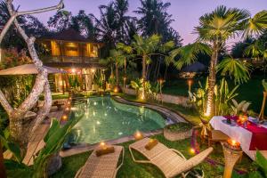 an outdoor pool with chairs and a house at Gusde Tranquil Villas by EPS in Ubud