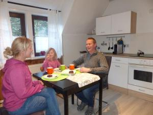 grupa ludzi siedzących przy stole w kuchni w obiekcie Ferienwohnung Schelhorn w mieście Mengersgereuth-Hämmern