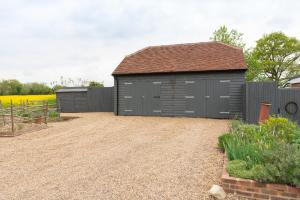 a grey garage with a fence and a gravel driveway at The Old Engineer A rural boutique retreat in Yalding