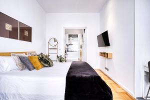 biała sypialnia z dużym łóżkiem z czarną ławką w obiekcie Atocha-Sol Boutique w Madrycie