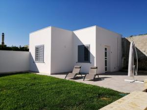 een wit huis met 2 stoelen op een patio bij Villa Cleofe in Tuglie