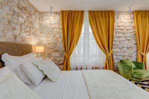a bedroom with a large bed with yellow curtains at Princ Heritage Rooms in Split