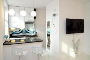 a kitchen with white cabinets and a tv on a wall at Apartament Domi in Gniezno
