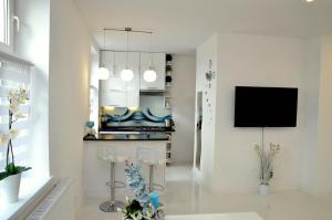 a living room with white walls and a tv on a wall at Apartament Domi in Gniezno