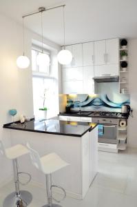 uma cozinha com armários brancos e um balcão preto em Apartament Domi em Gniezno