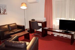 uma sala de estar com um sofá, uma secretária e uma televisão em Hotel Donnersberg em Darmstadt