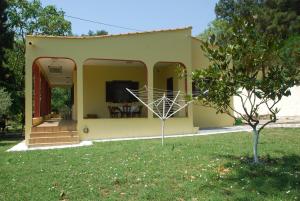 una pequeña casa amarilla con un árbol en el patio en Ktima Garidis, en Kavala