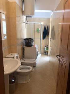 ein Badezimmer mit 2 WCs, einem Waschbecken und einer Dusche in der Unterkunft MiMi's Beach Apartment in Vlorë