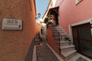 un callejón con escaleras y una señal en el lateral de un edificio en La casa di Duilia, en Fornelli