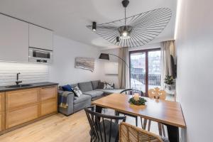 uma cozinha e sala de estar com uma mesa e um sofá em Apartament Wierchy em Zakopane