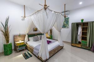 a bedroom with a bed with a mosquito net at MasBro ART Villas in Seminyak