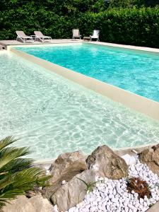 una piscina con 2 sillas y algunas rocas en Villa Don Camillo, en Sant'Agnello