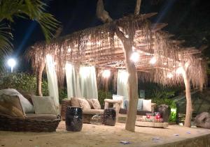 a room with couches and a palm tree with lights at Le Château de feuilles in Baie Sainte Anne