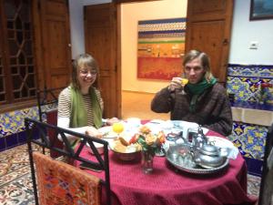 Duas mulheres sentadas à mesa a comer comida. em Dar Halima em Essaouira