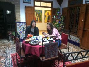 zwei Frauen sitzen an einem Tisch vor einem Weihnachtsbaum in der Unterkunft Dar Halima in Essaouira