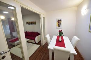 Cette chambre comprend une table blanche et un canapé rouge. dans l'établissement Gardos house above Danube, à Belgrade