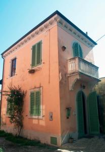 ein orangefarbenes Gebäude mit grünen Rollläden und einem Balkon in der Unterkunft Il Balconcino sulle Terme in San Giuliano Terme
