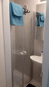bagno con doccia, lavandino e asciugamani blu di Orange Cube Apartment - Self check in - Free parking a Fiume (Rijeka)