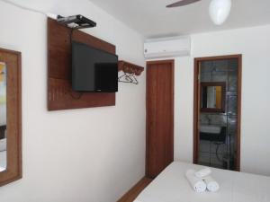 a room with a tv on the wall and a bed at Pousada Amaryllis in Tiradentes