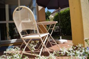 two chairs sitting on a patio under an umbrella at Liebevoll eingerichtete Ferienwohnung am Rande von Berlin in Blankenfelde