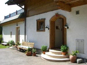 a house with a bench and potted plants in front of it at Appartement Klinger in Eben im Pongau