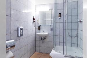 a bathroom with a toilet, sink, and shower stall at Hotel Eden am Zoo in Berlin