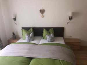 a bedroom with a large bed with green and white pillows at Haus am Wald in Neustift im Stubaital