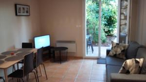 uma sala de estar com um sofá, uma mesa e uma televisão em Appartement dans propriété calme en pleine nature em Charbonnières-les-Bains