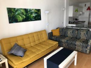 ein Wohnzimmer mit einem gelben Sofa und einem Tisch in der Unterkunft Calle del Sol Bajamar Apartment in La Laguna