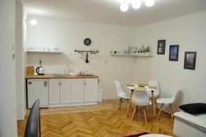 Zvekir - Old Town Apartment في سراييفو: مطبخ مع خزائن بيضاء وطاولة وكراسي