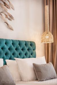 a bed with a green tufted headboard and a lamp at Kalidon Panorama Hotel in Kokkari