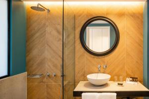 W łazience znajduje się umywalka i lustro. w obiekcie Kalidon Panorama Hotel w mieście Kokkari