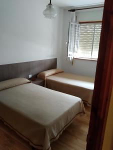 two beds in a small room with a window at HOSTAL RESIDENCIA PRESIDENTE in Ribadeo