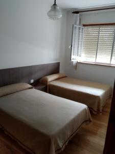 Duas camas num pequeno quarto com uma janela em HOSTAL RESIDENCIA PRESIDENTE em Ribadeo