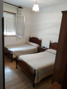 a room with two beds and a window at HOSTAL RESIDENCIA PRESIDENTE in Ribadeo