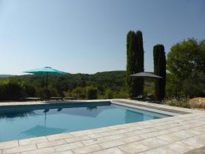 una piscina con sombrilla y algunos árboles en Mas des trois citernes, en Saint-Jean-de-Maruéjols-et-Avéjan