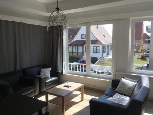 a living room with couches and a large window at « Les 3 Moussaillons » appartement 2 ch Coxyde in Koksijde