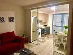 ein Wohnzimmer mit einem roten Sofa und einer Küche in der Unterkunft Apartamentos Turísticos Casa Dina in Rinlo + 31 Fotos