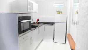 a white kitchen with white cabinets and appliances at Ocean BAYALOCATION in LʼAnse Mitan