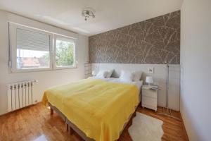 a bedroom with a large bed with a yellow bedspread at Apartman Osijek in Osijek