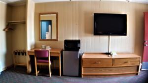 Habitación de hotel con TV, escritorio y mesa. en Grand Motel, en Hastings