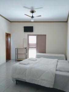 a white bedroom with a bed and a ceiling fan at Pousada Deus é Fiel in Cachoeira Paulista