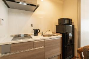 una pequeña cocina con fregadero y nevera. en GRAND BASE Beppu, en Beppu