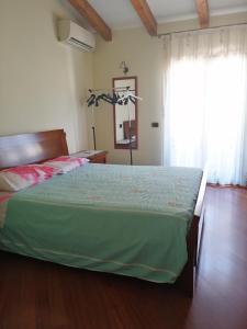 1 dormitorio con 1 cama con edredón verde y ventana en casa bijoux, en Itri