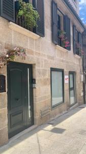 un edificio de piedra con una puerta verde y ventanas en Virginia Redondela, en Redondela