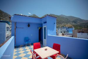 a blue house with a table and chairs on a balcony at Casa El Mrabet in Chefchaouene