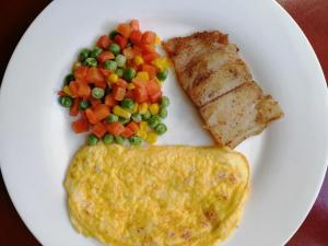 Un plato blanco con tortilla y verduras. en Mariner's Pension House en Puerto Princesa