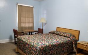 a bedroom with a bed and a table and a chair at Economy Inn in Lumberton